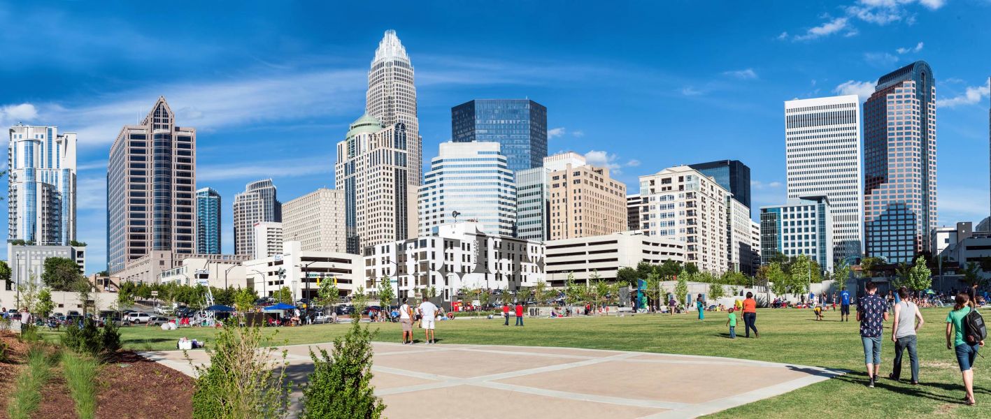 500 West Trade apartments in Charlotte, NC bustling cityscape with people in a park with a large grassy field