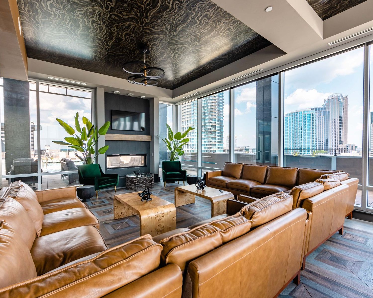 500 West Trade luxury apartments building interior community amenities lounge with couches, chairs, tables, and a plant with a view of the city