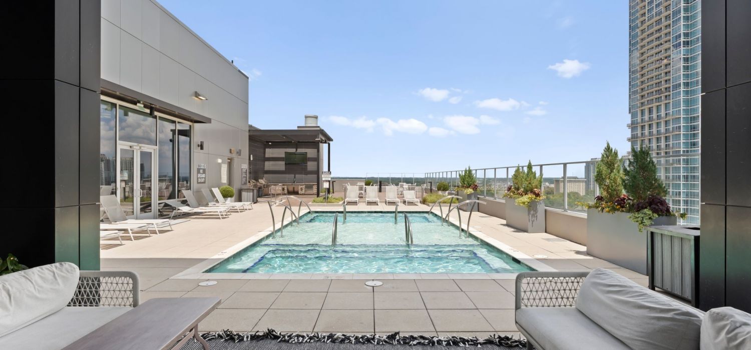 500 West Trade luxury apartments building building exterior community amenities rooftop pool deck outdoor lounge area with couches, a fireplace, and a TV