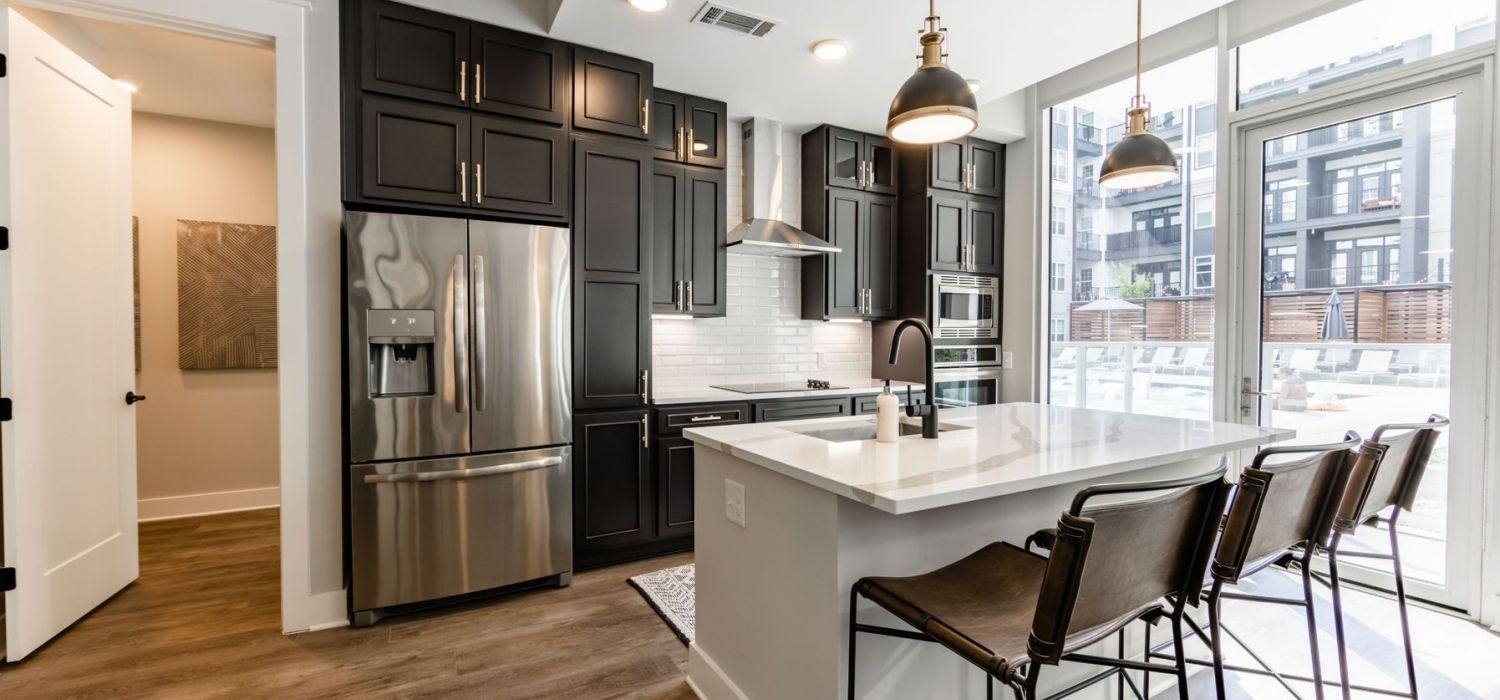 500 West Trade luxury apartment kitchen with island, bar stools, and floor to ceiling custom cabinets, and faux wood flooring