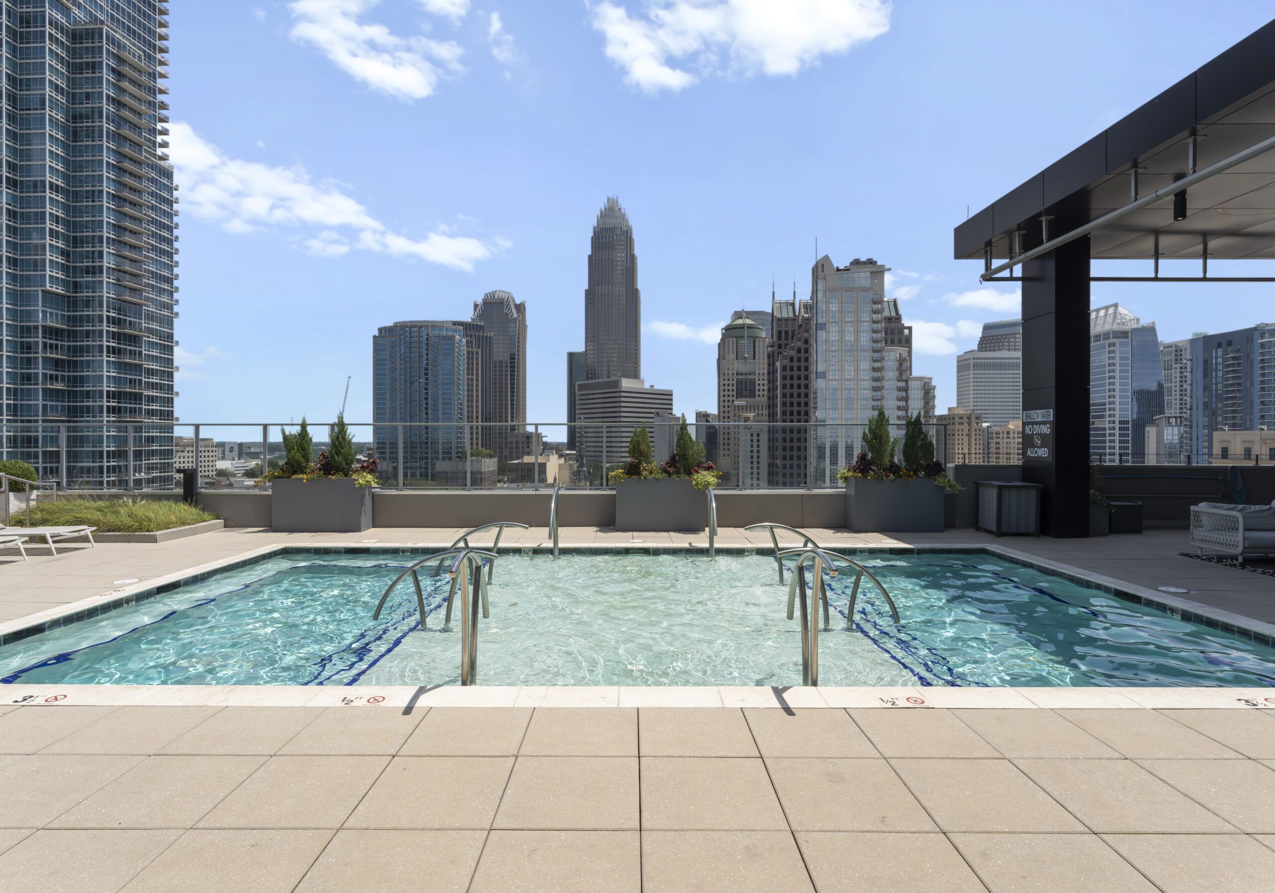 500 West Trade luxury apartments building exterior community amenities rooftop pool and hot tub with beautiful view of the city line and skyscrapers