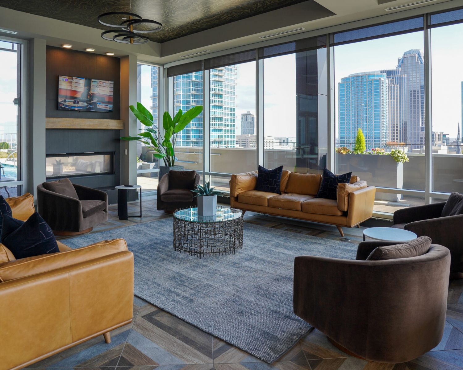 500 West Trade luxury apartments building interior community amenities lounge with couches, chairs, tables, and a plant with a view of the city