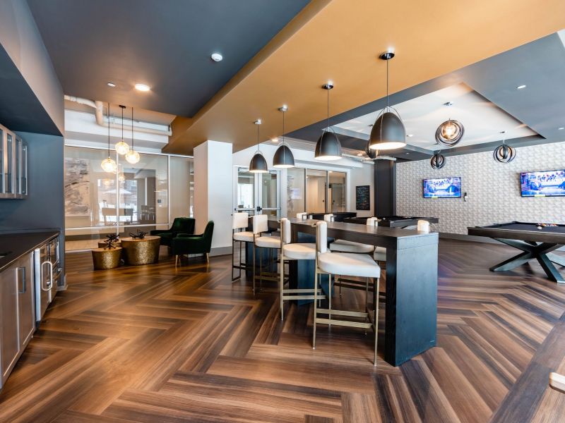 500 West Trade Apartments community amenities lounge and game room with bar seating, games, chairs, pool table, and two TVs