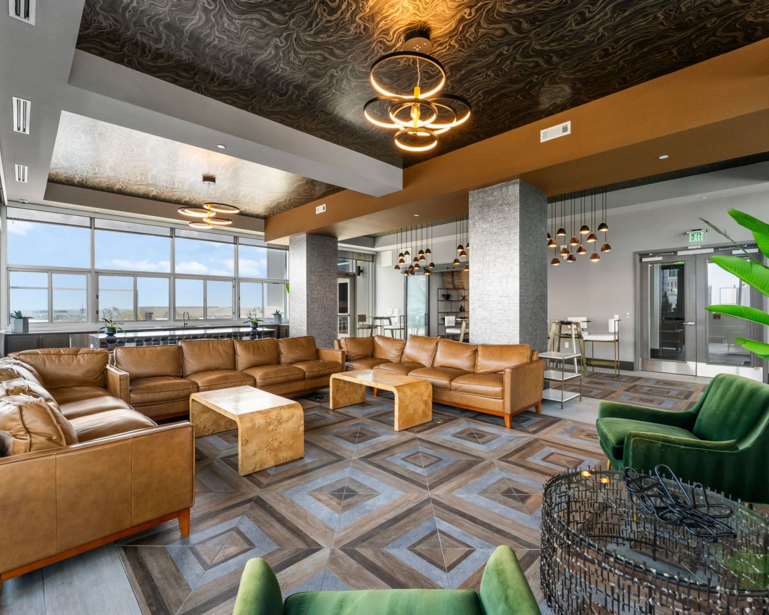 500 West Trade luxury apartments building interior community amenities lounge with couches, chairs, tables, and a plant with a view of the city