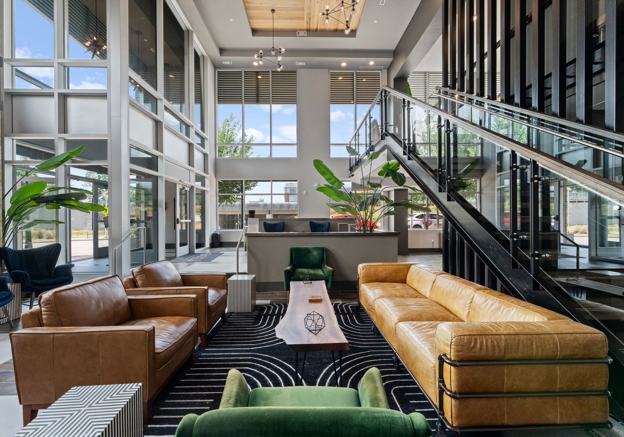 500 West Trade luxury apartments building building interior community amenities lounge with couches, chairs, tables, and a plant with a view of the city