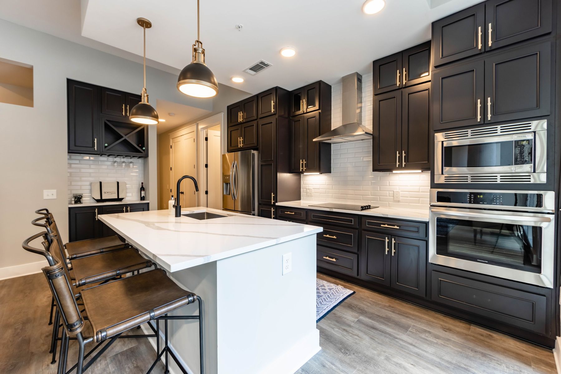 500 West Trade luxury apartment kitchen with island, bar stools, and floor to ceiling custom cabinets, and faux wood flooring