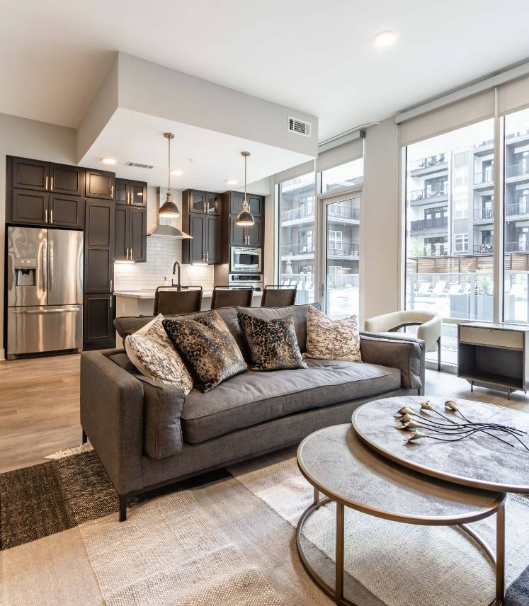 500 West Trade luxury apartment living room with couch, coffee table, rug, faux wood flooring and large windows with nice natural light