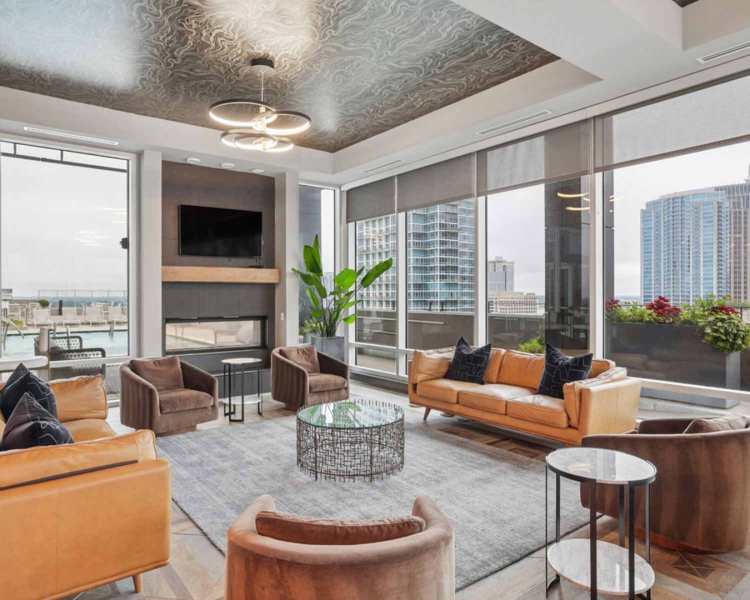 500 West Trade luxury apartments building interior community amenities lounge with couches, chairs, tables, and a plant with a view of the city