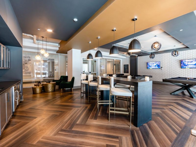 500 West Trade Apartments community amenities lounge and game room with bar seating, games, chairs, pool table, and two TVs
